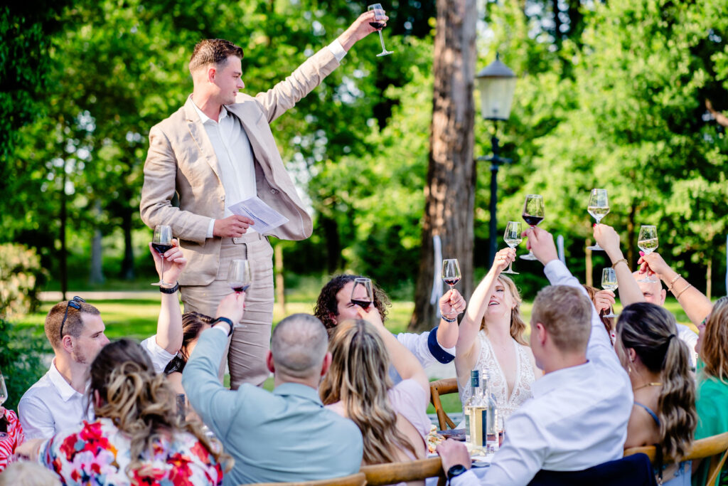 Getuige proost op het bruidspaar tijdens het diner georganiseerd door de ceremonie meester die het bruidspaar inhuren.