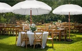 SOTS Verhuur setup met ronde tafels, houten stoelen en witte parasols voor buitenevenement in Twente